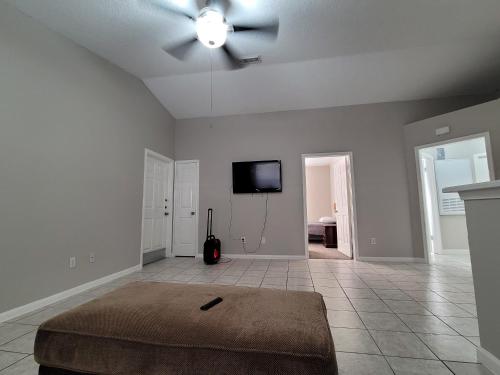 a living room with a ceiling fan and a tv at Fresh CrashPads 2 in Houston