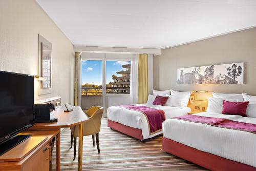a hotel room with two beds and a flat screen tv at Leonardo Royal Hotel Frankfurt in Frankfurt/Main