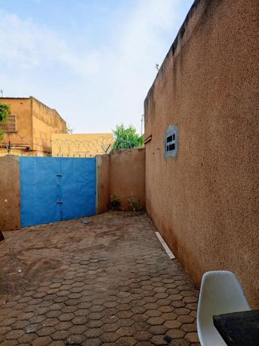 un callejón con una pared con una puerta azul en La MAISONNETTE, en Ouagadougou