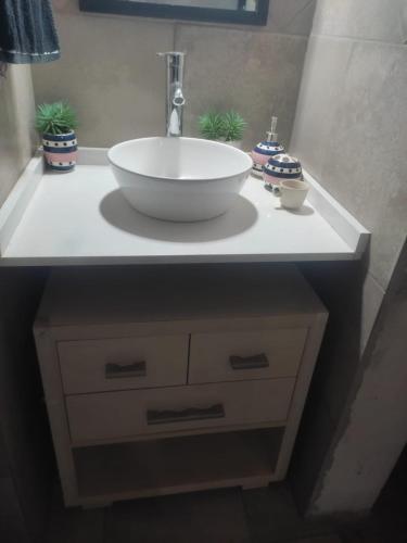 a bathroom sink with a white bowl on a counter at Aldea La Abundancia Cabaña Hostel in La Falda