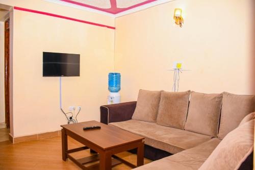 a living room with a couch and a table at Hossanah Furnished one bedroom in Kasarani,Nairobi in Nairobi