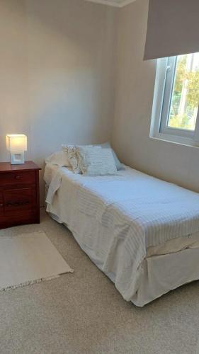 a bedroom with a bed with a nightstand and a window at CasaNativa 7Sur in Curicó