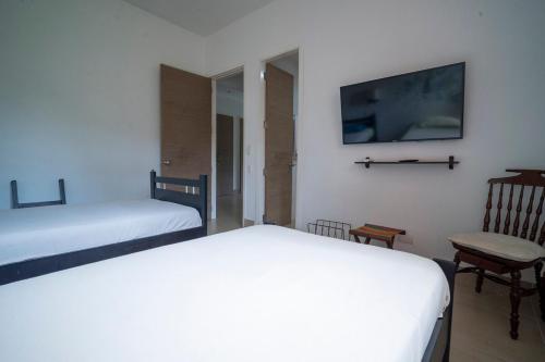 a bedroom with two beds and a tv and a chair at wonderful house in Marina Baru in Cartagena! in Isla Barú