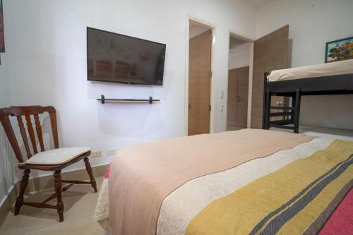 a bedroom with a bed and a chair and a tv at wonderful house in Marina Baru in Cartagena! in Isla Barú