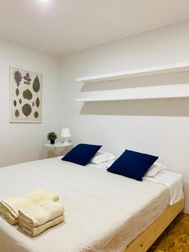 a white bedroom with a large white bed with blue pillows at Casa Devesas in Vila Nova de Gaia