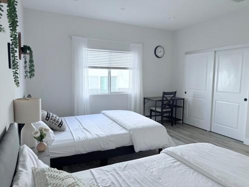 a bedroom with two beds and a clock on the wall at Modern Family Haven - Minutes from Disney Magic-OC in Midway City