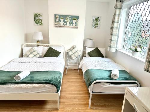 two beds in a small room with a window at 3 Twin Bedroom Entire House Sleeps 10 Driveway Parking near Coventry University and City Center in Coventry