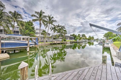 a boat is docked in a canal with palm trees at Waterfront Marco Island House with Shared Dock! in Marco Island