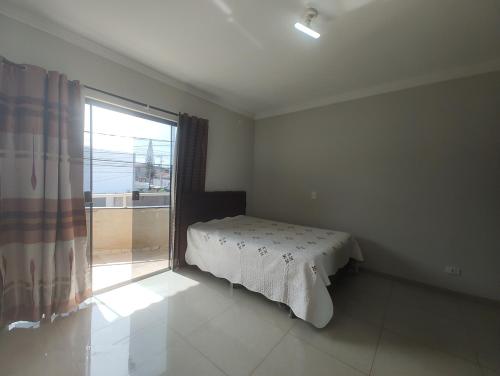 a bedroom with a bed and a large window at Sobrado para show rural in Cascavel