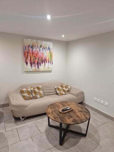 a living room with a couch and a table at Appartement T2 Avec Terrasse PROCHE GROUPAMA STADIUM AEROPORT ST EXUPERY LDLC ARENA EUREXPO in Pusignan