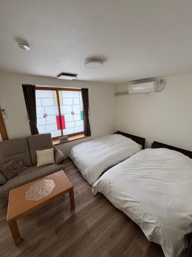 a living room with two beds and a couch at Mountain Gate FURANO in Kami-furano