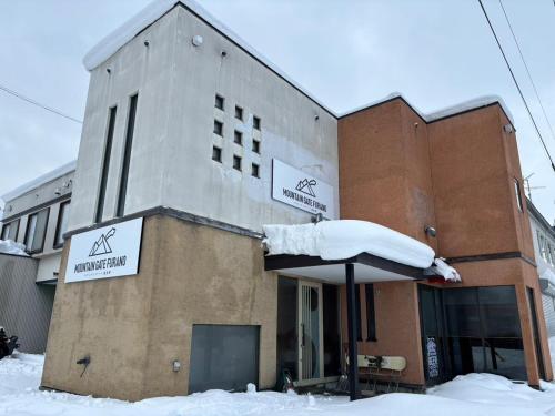 a building with an umbrella in the snow at Mountain Gate FURANO in Kami-furano