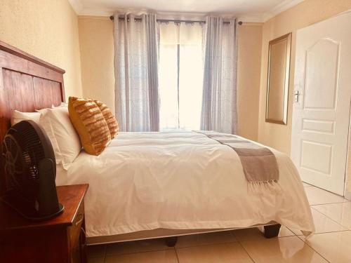 a bedroom with a white bed with a window at MBT Guesthouses in Ga-Mothiba