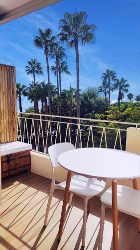 un balcon avec une table, des chaises et des palmiers dans l'établissement La Dolce Vita de Cannes: Luxury city center apartement, beautiful View, à Cannes