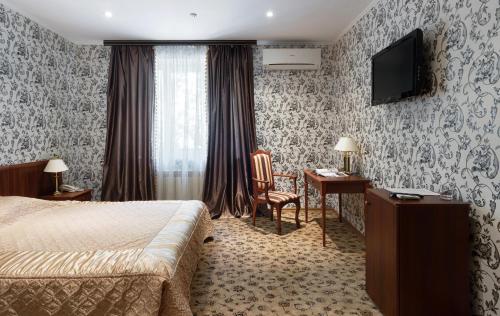 a hotel room with a bed and a desk and a television at Britaniya in Kharkiv