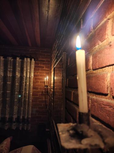 a candle in a room with a brick wall at Pousada Romântica Serra da Mata in Penedo