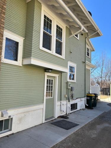 a green house with a green door on a street at Trendy Craftsman Studio with Firepit and Laundry! in Willmar
