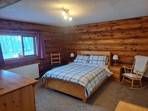 a bedroom with a bed and a wooden wall at Smithers Driftwood Lodge in Smithers