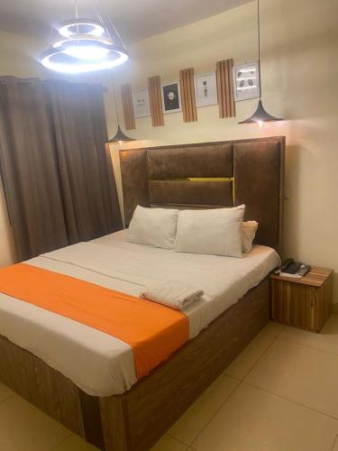 a bedroom with a large bed with an orange blanket at Ontario Suites in Lagos