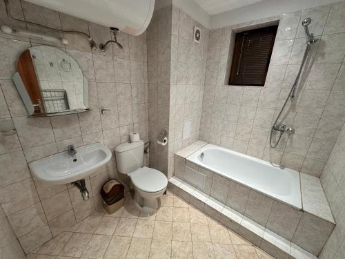 a bathroom with a tub and a toilet and a sink at Private apartment in Prespa in Bansko
