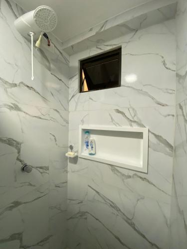 a bathroom with white marble walls and a tv at Makani Flat Campas in Tamandaré