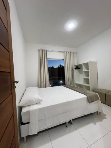 ein weißes Schlafzimmer mit einem großen Bett und einem Fenster in der Unterkunft Casa céu de estrelas in Arraial d'Ajuda