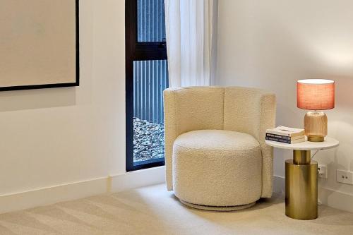 a chair sitting next to a table with a lamp at Family-Friendly 3 Levels Architect Home Near Airport Beach Sydney City FREE City Parking & Airport Pickup Available in Sydney