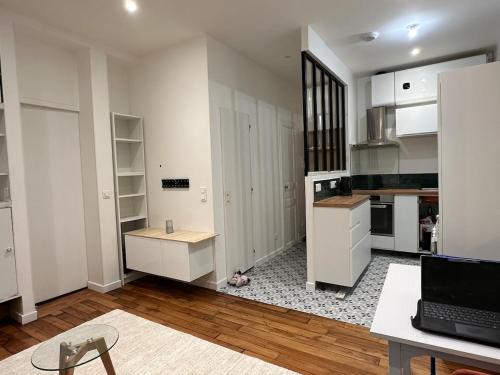 une cuisine avec des placards blancs et un ordinateur portable sur une table dans l'établissement Casa Preciosa, à Ivry-sur-Seine