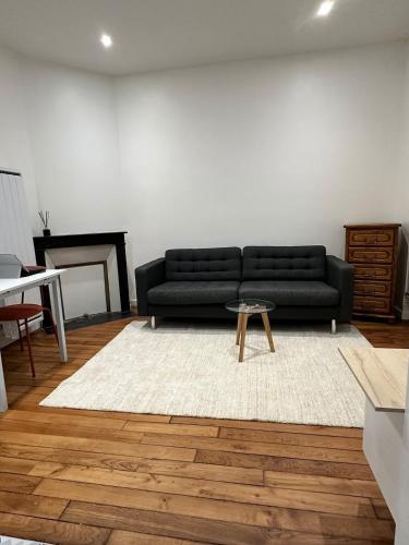 un salon avec un canapé noir et une table dans l'établissement Casa Preciosa, à Ivry-sur-Seine