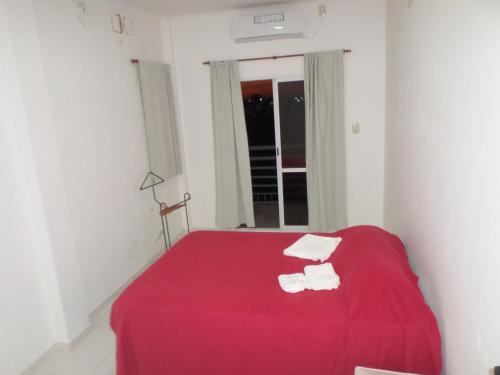 a bedroom with a red bed with two white towels at EL JACARANDÁ in Charata