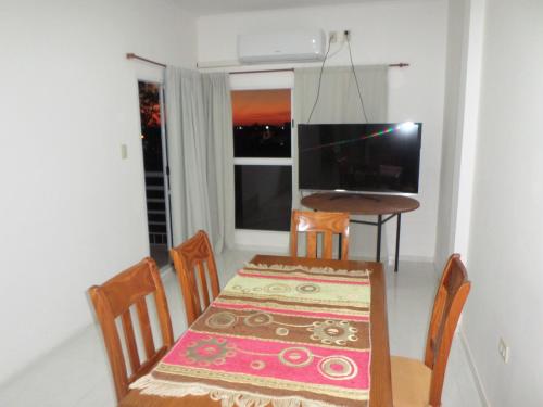 a dining room with a table and chairs and a television at EL JACARANDÁ in Charata
