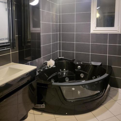 La salle de bains est pourvue d'une baignoire noire et d'un lavabo. dans l'établissement Villa TON PARADIS - 4 chambres, à La Villeneuve