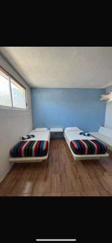 Ce lit se trouve dans un dortoir doté de murs bleus et de parquet. dans l'établissement La Casa De La Abuela, à Zihuatanejo