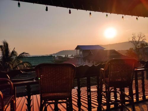a table and chairs with the sunset in the background at Sophea's guesthouse in Kaôh Kon