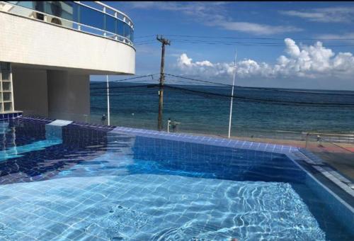 a swimming pool with a view of the ocean at Apartamento Ondina Salvador in Salvador