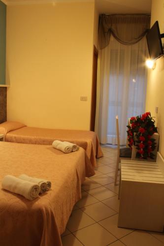 a hotel room with two beds and a vase of flowers at Hotel Senyor in Rimini