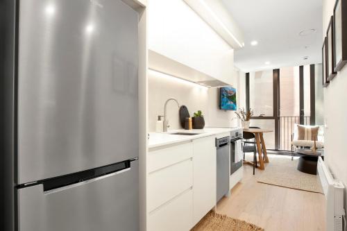 a kitchen with white cabinets and a refrigerator at Perfectly Paired - Your Dual Apartment Escape in Wellington