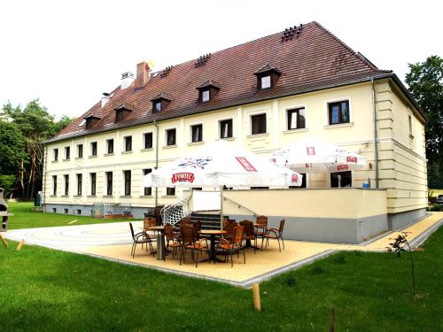 a table with chairs and umbrellas in front of a building at Hotel Świętoborzec in Łobez