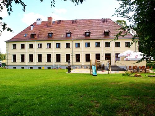 a large building with a grass field in front of it at Hotel Świętoborzec in Łobez