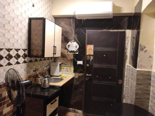 uma cozinha com um lavatório e uma porta preta em غرف نوم فى فندقية بها ما الزمالك em Cairo
