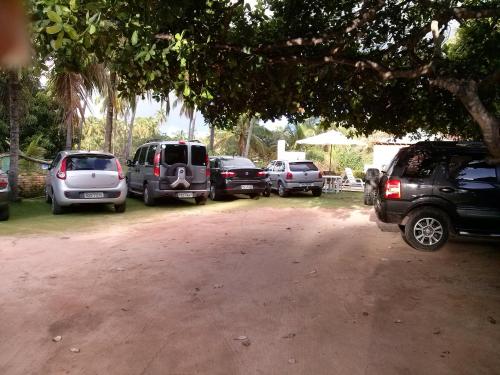 a group of parked cars parked under a tree at Pousada Lua Cheia in Japaratinga