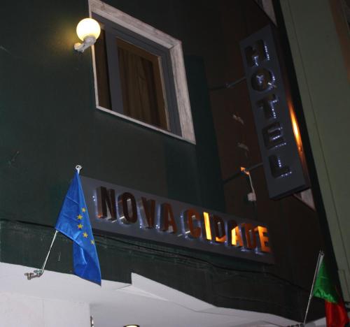 a sign on the side of a building with a flag at Hotel Nova Cidade in Amadora