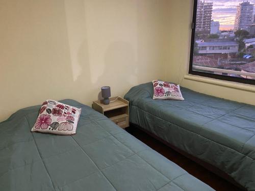 two beds in a room with a window at Acogedor y amplio departamento central in Temuco