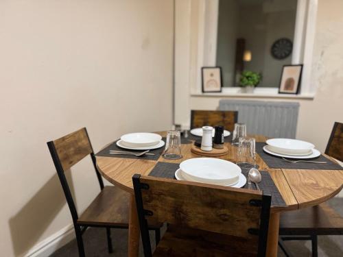 a wooden table with chairs and plates on it at The Accrington Haven in Accrington
