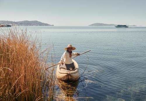 a man is rowing a canoe in the water at Titilaka by Andean in Tililaca