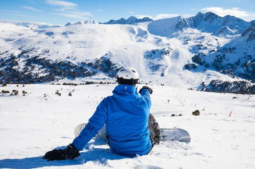 a person sitting in the snow with a snowboard at En el corazón de Canillo, junto al Puente Tibetano in Canillo