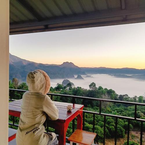 a child sitting at a table looking out at the view at บ้านชมหมอก ภูลังกา in Ban Sakoen