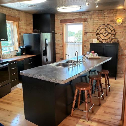 a kitchen with a large counter with a sink and stools at THE LOFT 3 level urban cabin with a HUGE patio! in Willmar