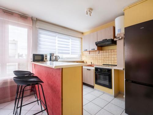 une cuisine avec des placards jaunes et rouges et un réfrigérateur noir dans l'établissement Le Chatoyant - À 15 minutes de la Place Stanislas - NyuLocation, à Nancy