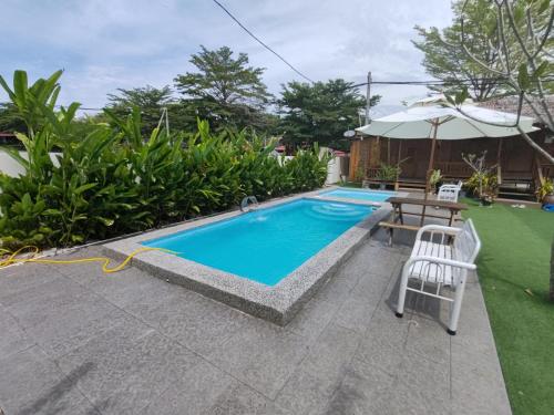 a pool with a table and chairs next to a house at Aeden Villa Roomstay & Homestay in Kuala Kangsar